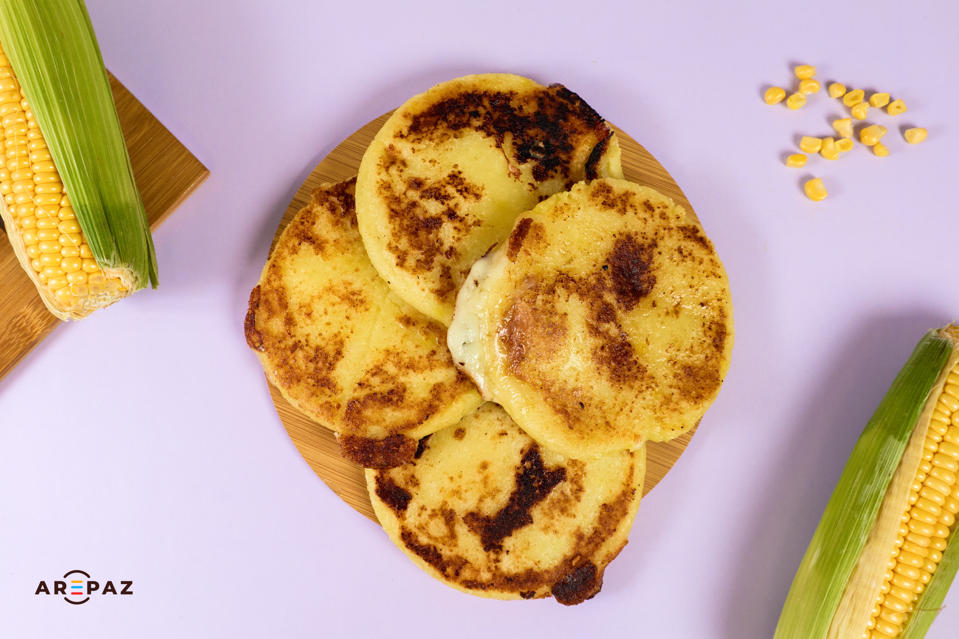 Freshly made arepas with corn on lavender background